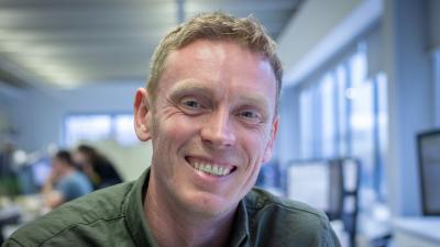 Headshot of Paul Thornborough. A smiling man wearing an olive green shirt.