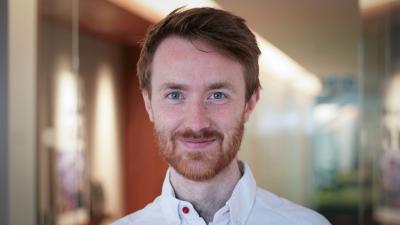 Headshot of Sebastian Chambers. A man smiling, wearing a white shirt.