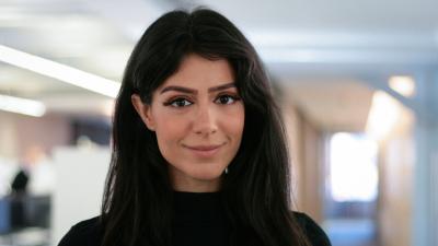 Headshot of Shaadi Karimi. A smiling woman with long dark hair wearing a black jumper.