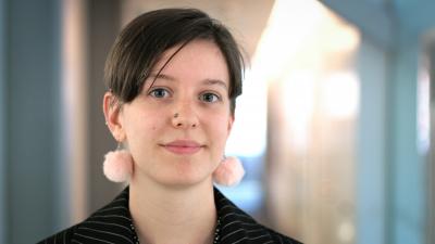 Headshot of Daisy Winter. A woman with short brown hair and pink earrings.