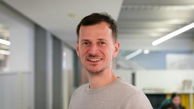 Headshot of Steve Kendall. A man smiling at the camera, wearing a grey t-shirt.