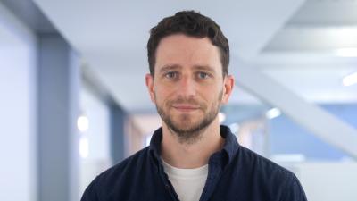Headshot of Edward Pryce, a man wearing a black shirt and white tee.