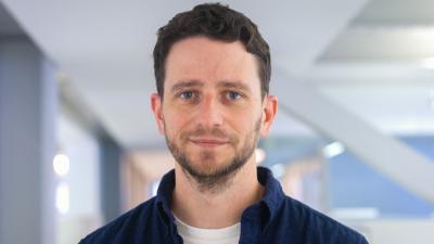 Headshot of Edward Pryce, a man wearing a black shirt and white tee.