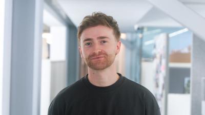 Headshot of Will Dingwall, a man wearing a black jumper looking at the camera