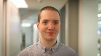 Headshot of Will Rawling. A man wearing a buttoned up shirt.