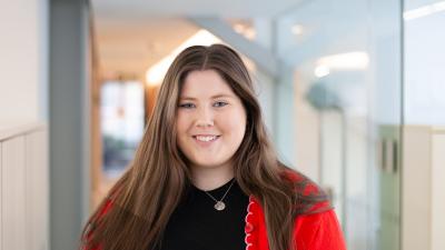 Headshot of Heather Davies, a woman with long dark hair wearing a red cardigan