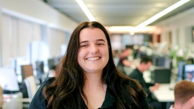 A headshot of a girl with dark hair standing in an office.