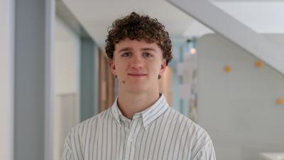 Young man with dark hair and striped shirt smiling