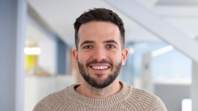 Headshot of Patrick Boyd. A man smiling, wearing an oatmeal jumper.
