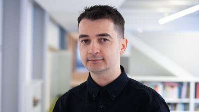 A man wearing a dark shirt and with dark hair in front of the camera