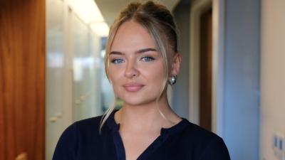 A woman in a black top and blonde hair, styled up, smiling.
