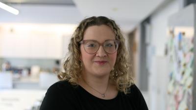 Woman with blonde curly hair wearing glasses.