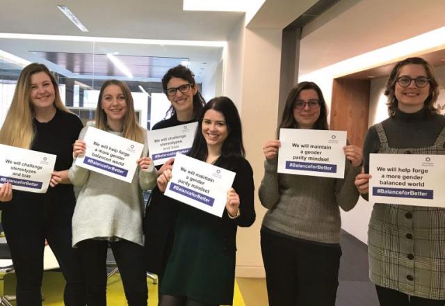 group of female staff posing with signs for balance for better