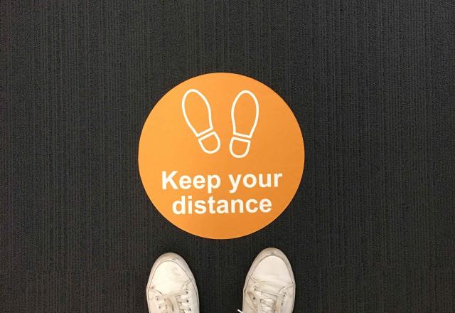 above view of floor sticker that reads 'keep your distance'