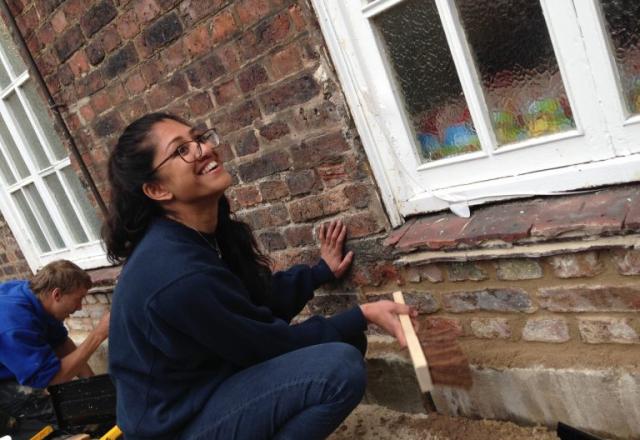 girl laughing whilst working on side of building