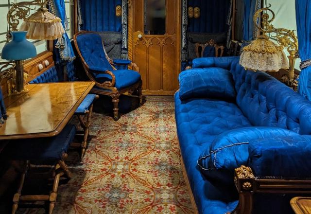 Interior image of Queen Victoria's lounge carriage. The furnishings and decor are a very rich blue. The ceiling is quilted fabric.