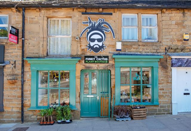 A shopfront with turquoise painted woodwork on a stone building