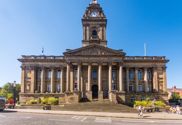 Morley Town Hall building. A dark brown stone building with columns and a clock tower