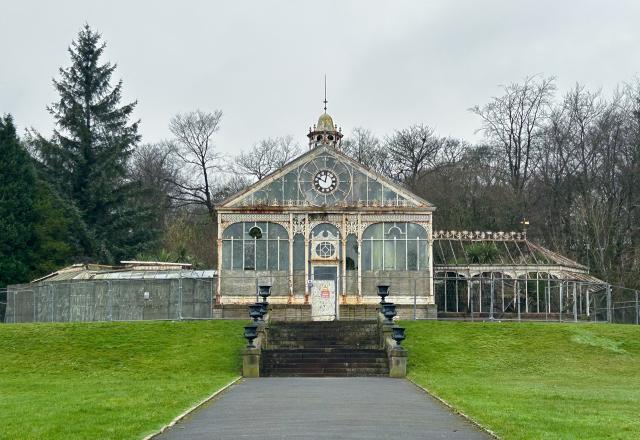 Blackburn Conservatory - a glass and white wood greenhouse style building on grass with trees behind.