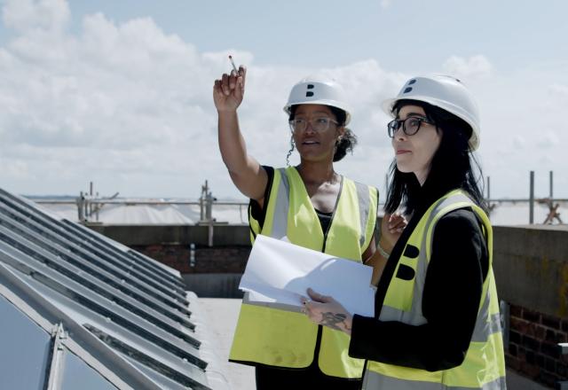 Photo of Lauren Gabbitas and Sam Knights, two women wearing high vis vests on the roof of a building