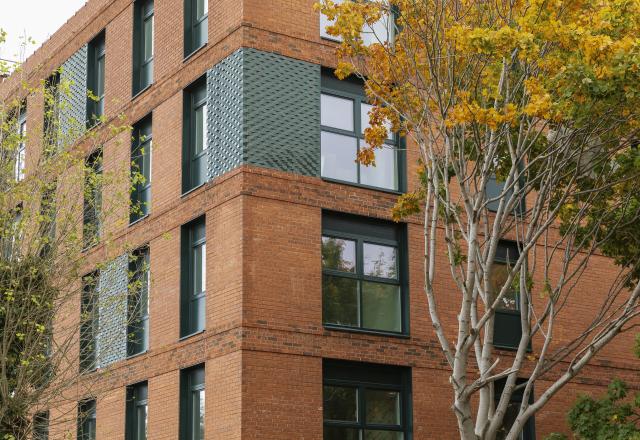 A red brick apartment block with trees outside.