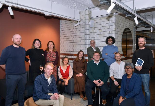 A group of people sitting and standing together looking at the camera.