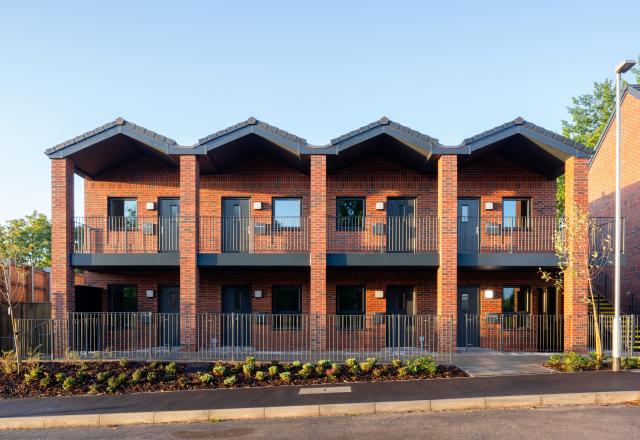 Red brick move on homes, a multi storey building with a grey walkway outside
