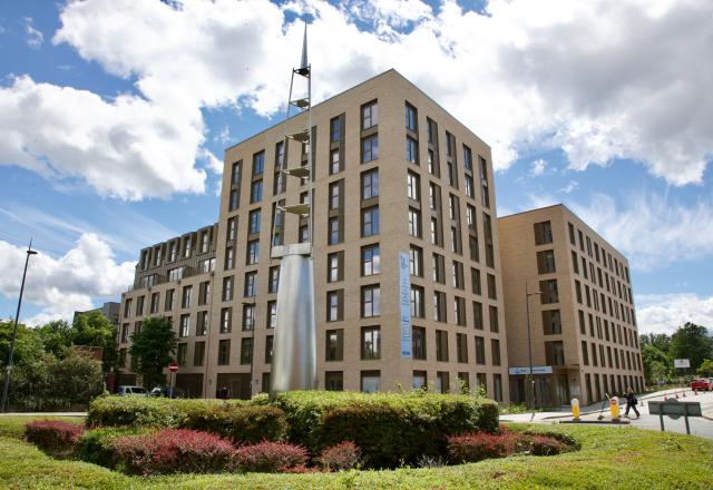 A large multi-storey residential apartment block with a green roundabout in front