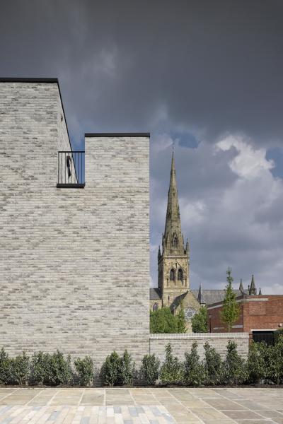 a grey brick wall frames the view of a church spire