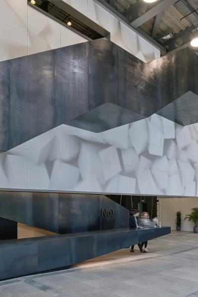 a black sculptural stair climbs in front of a digital screen