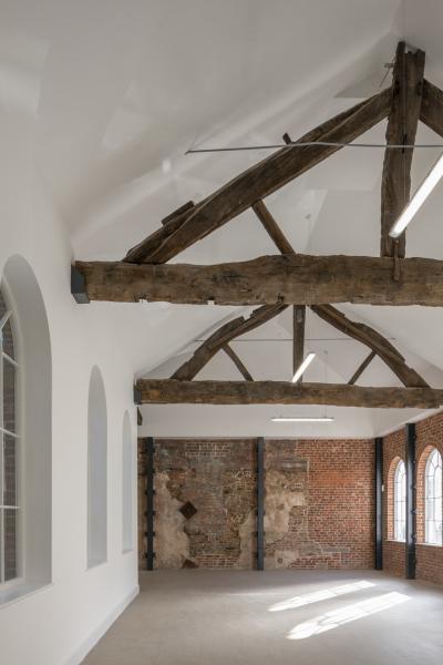 A brightly lit room with oak timber trusses.