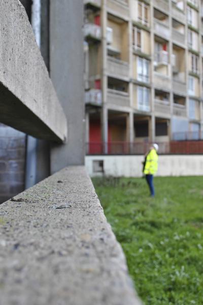a lady looks up towards a high rise housing block