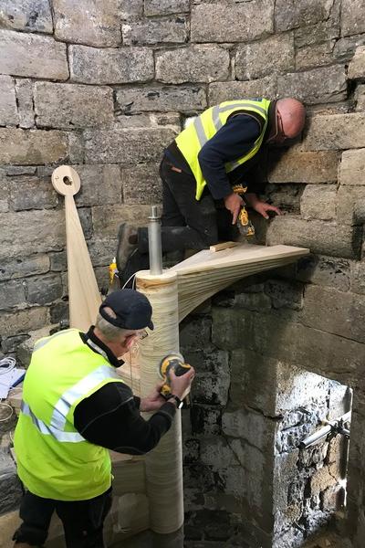 two men craft a timber spiral staircase