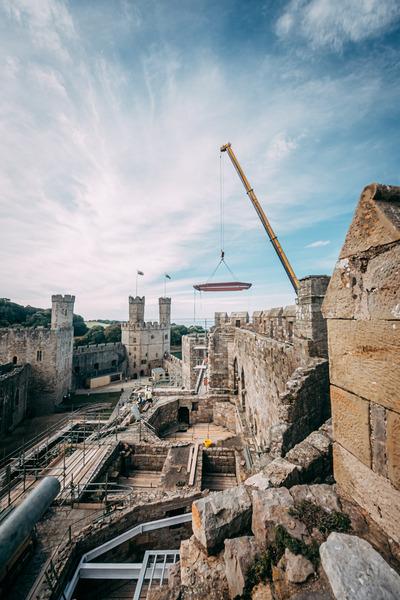a crane lifts a steel over the castle wall