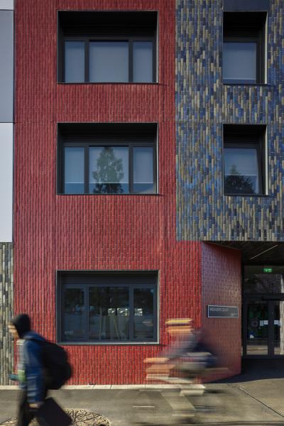 Person of riding a bike past an apartment building. 