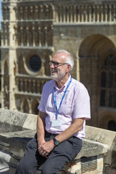 A man in a pink shirt sits in front of lincoln cathedral