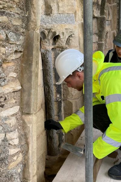 a man in a high vis jacket and hard hat working on a stone wall