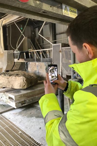 a man in a hi vis jacket is photographing a stone sample on a building site