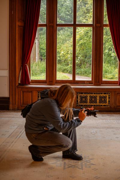 A lady is squatting taking a photo in a beautiful Georgian room
