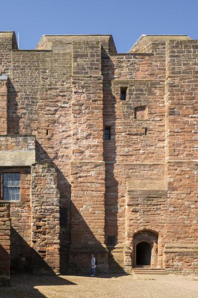 A large medieval type structure. It has no windows just a door at the ground level. It's a tall structure with five vertically running built elements. 