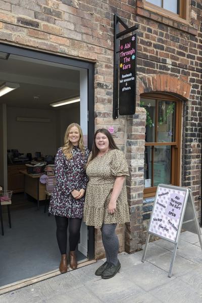 two ladies stand outside their shops on harper street