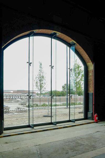 A view of the glazing from an interior, dark shot, with trains and carriages on exhibition. 