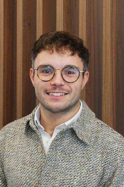 Toby Cope - man in a grey jacket and wearing glasses, smiling