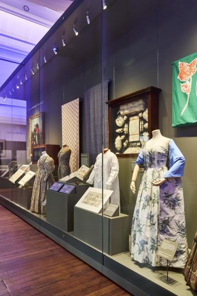Historical dresses inside a glass cabinet display.