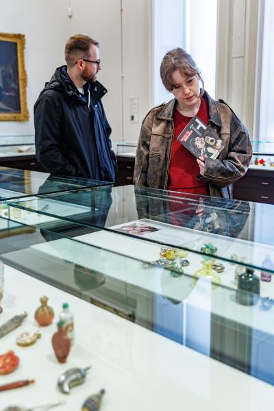 People looking at artefacts in a glass cabinet.