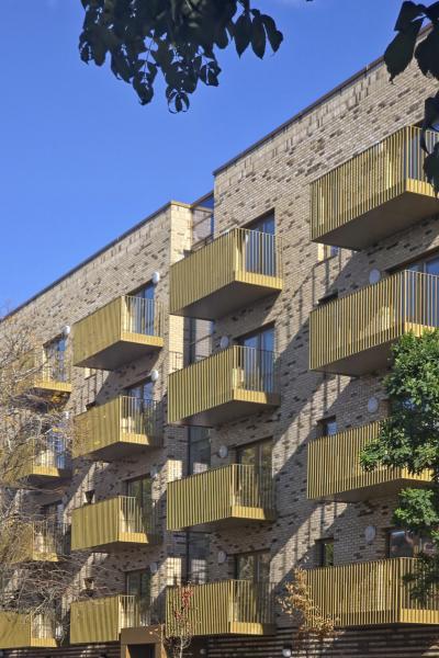 Balconies with a golden colour on the external side of a new light-brick apartment block
