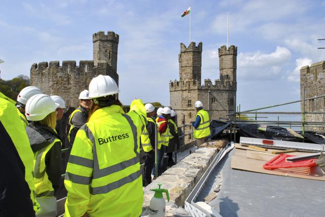 buttress staff in hi-vis with backs to camera admiring castle work