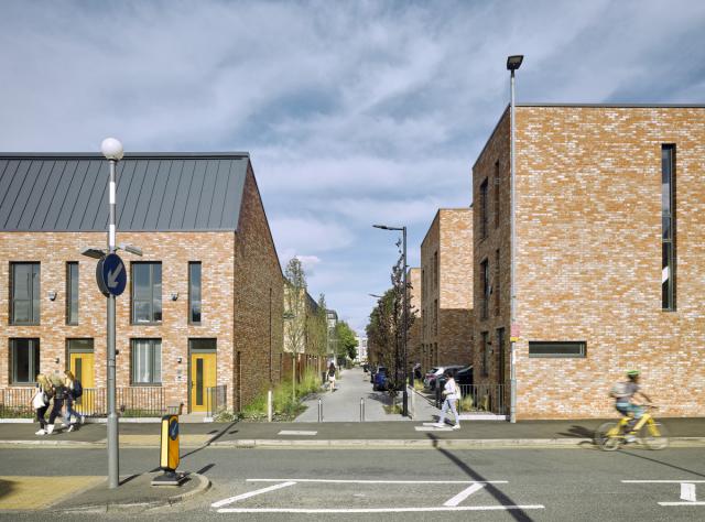 a view down a car free street between brick terraces