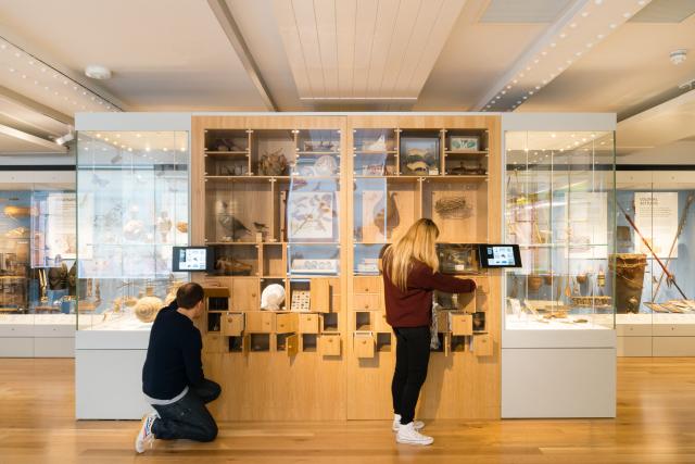 exhibition display at the higgins, two visitors interacting with display