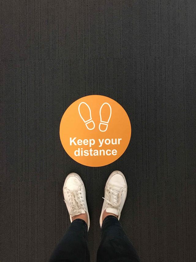 above view of floor sticker that reads 'keep your distance'